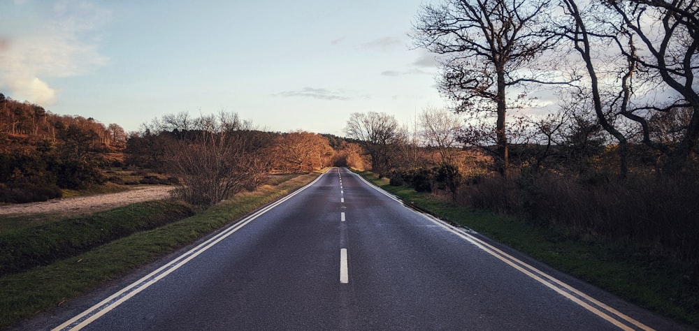 gray asphalt road between brown grass field during daytime