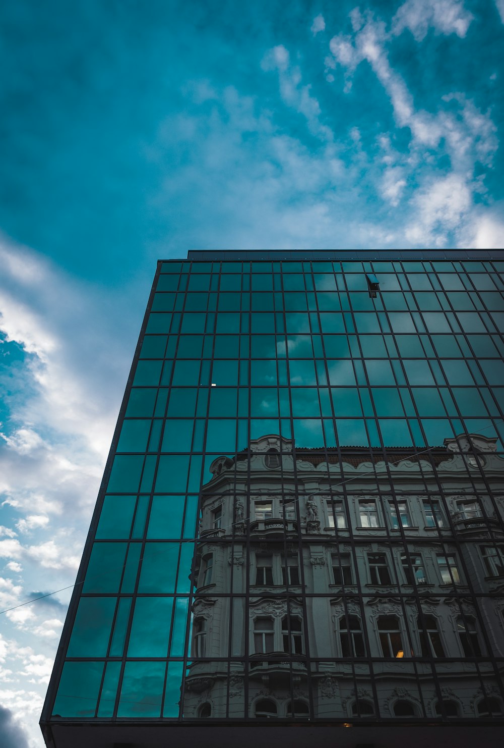 blue glass walled high rise building under blue and white cloudy sky during daytime