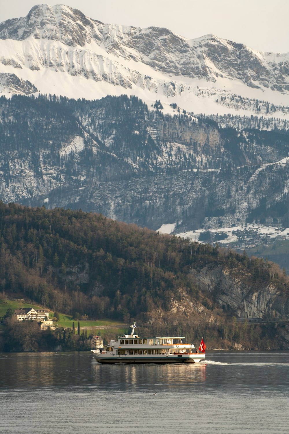 Casa bianca e marrone vicino agli alberi verdi e alla montagna coperta di neve durante il giorno