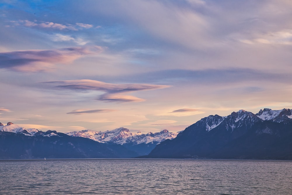 snow covered mountain near body of water during daytime