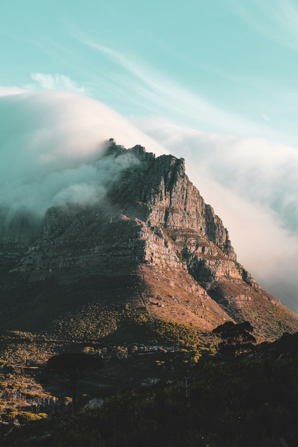 Montaña rocosa marrón bajo nubes blancas durante el día