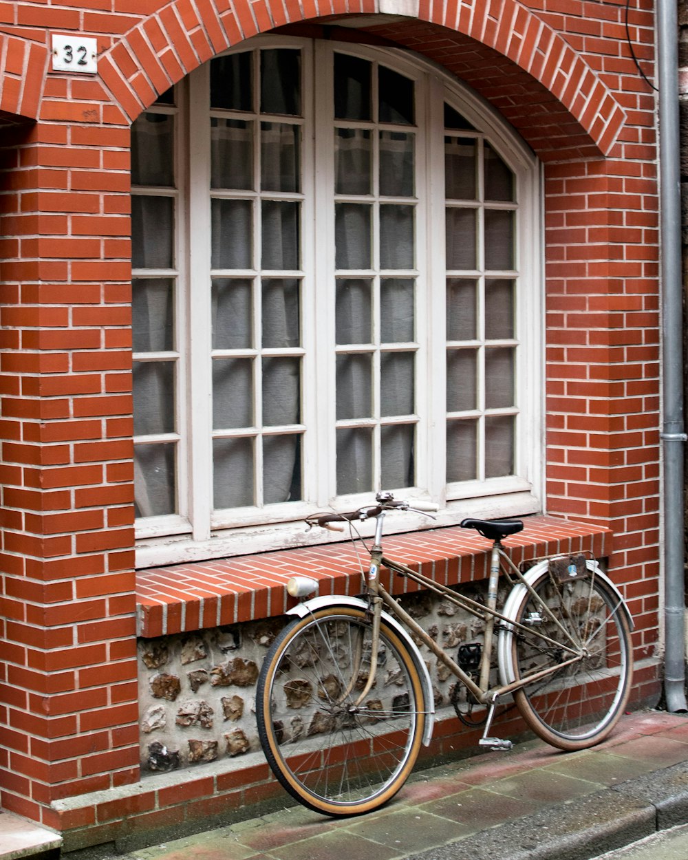 black city bike parked beside brown brick wall