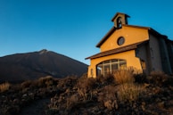A peaceful sunrise illuminating a small chapel where prayers are offered.