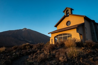 A peaceful sunrise illuminating a small chapel where prayers are offered.