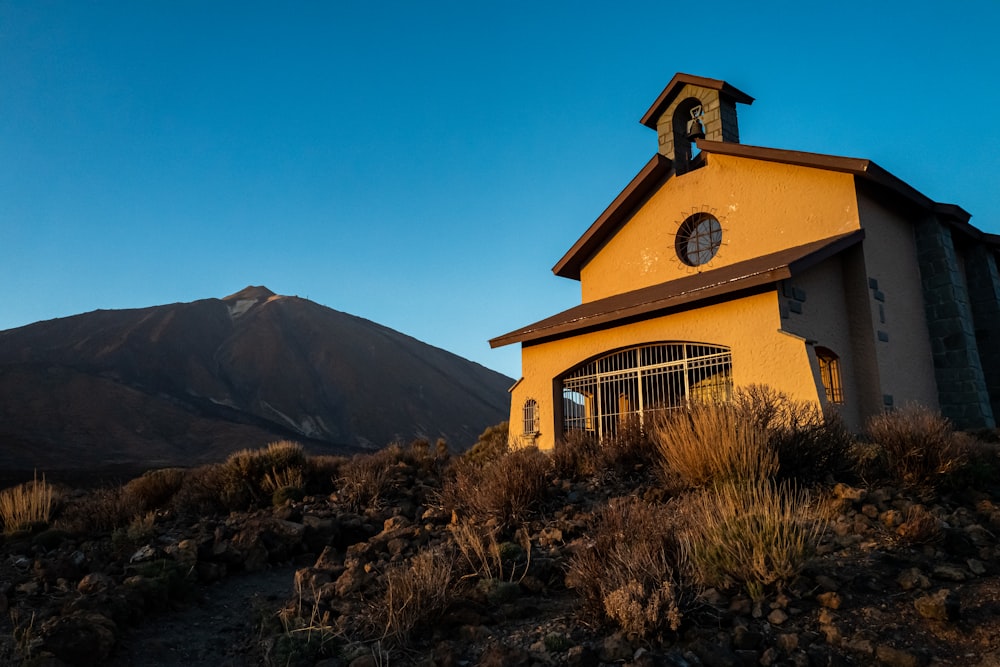 brown and white wooden house near mountain under blue sky during daytime