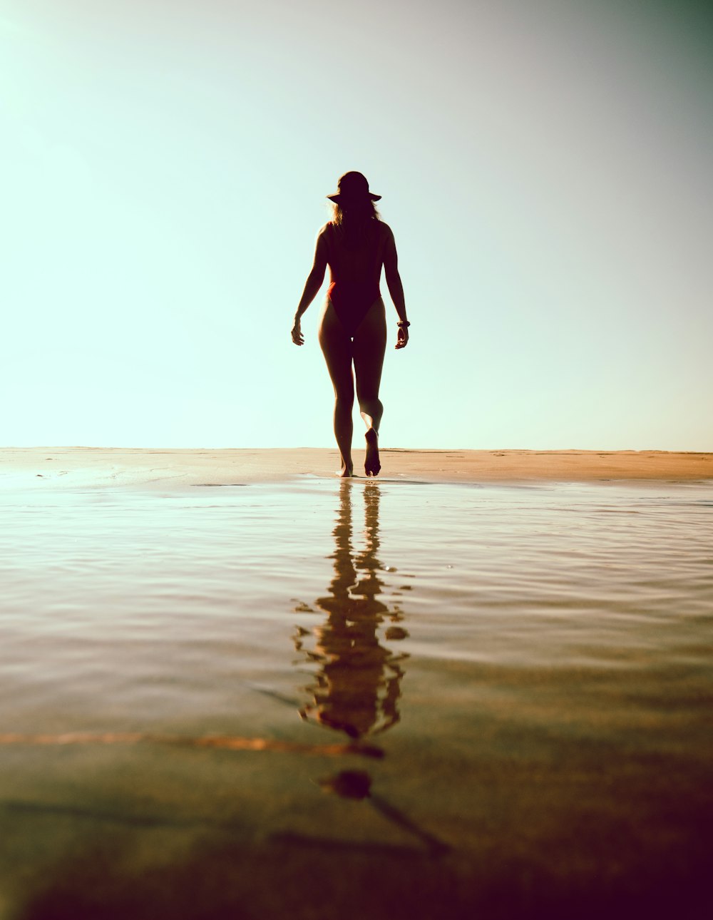 silhouette of woman walking on beach during sunset