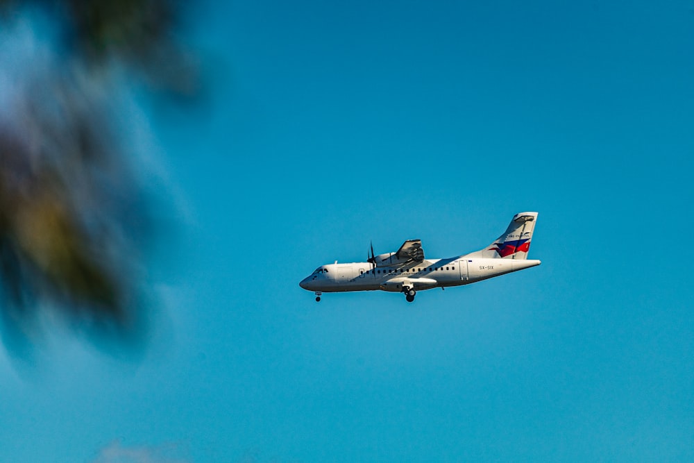 white and red airplane in mid air under blue sky during daytime