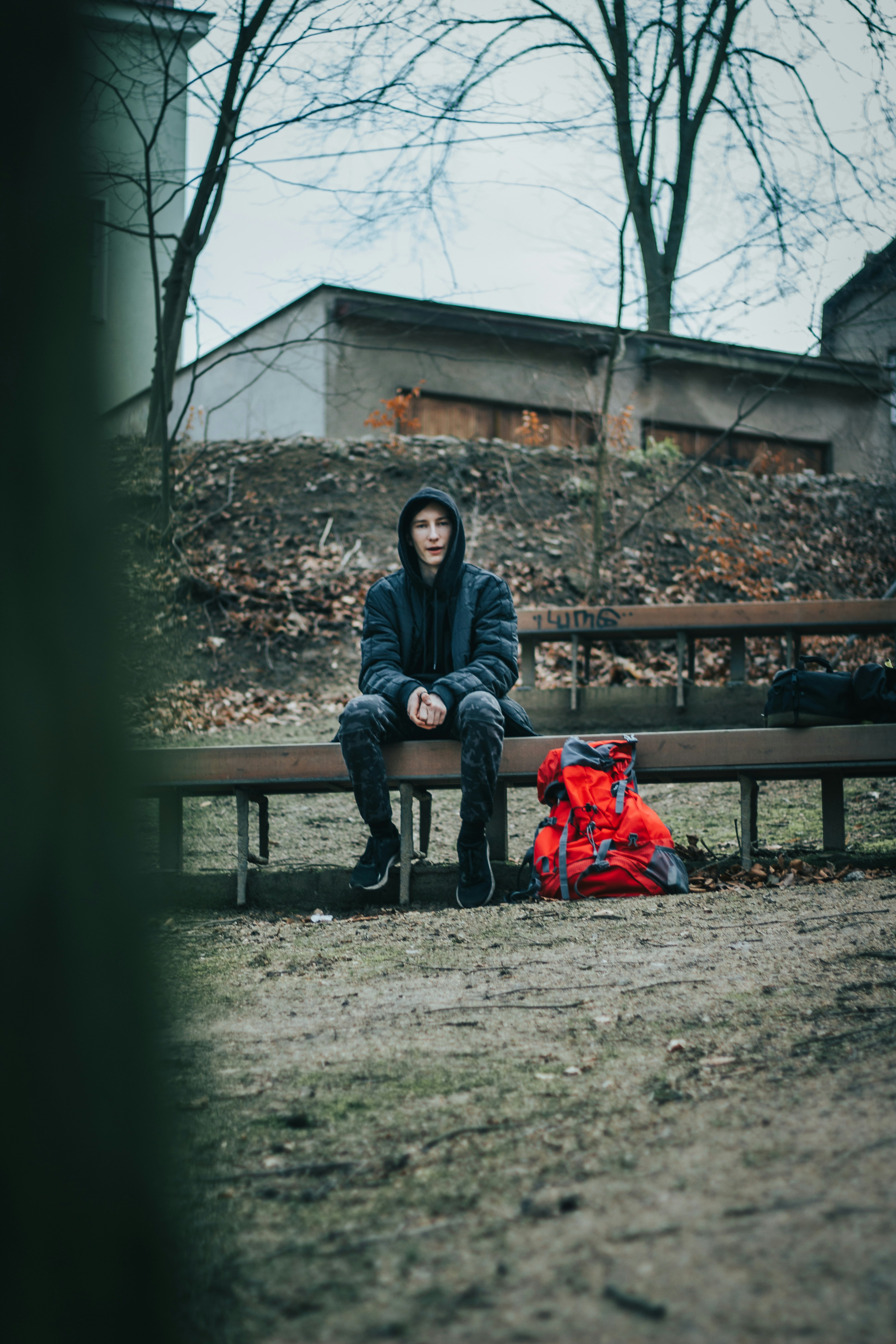 donna in giacca nera che si siede sulla panca di legno marrone