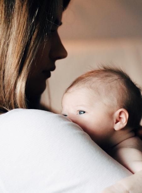 woman in white shirt carrying baby