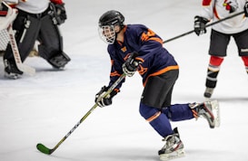 man in blue and white ice hockey jersey holding black and green hockey stick