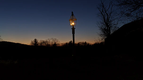 Solar-powered lamp posts brightening a peaceful village courtyard under a starry sky.