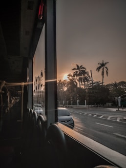 A serene desert sunset over Dubai's skyline with a luxury tour bus in the foreground.