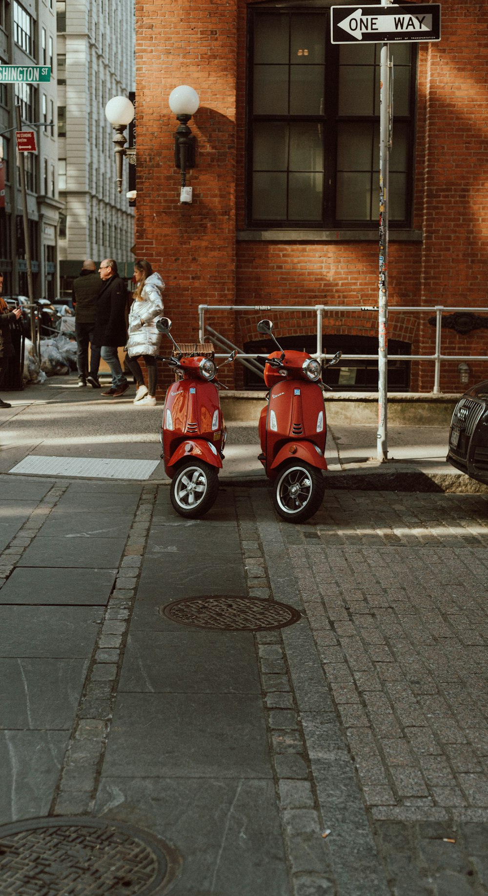 2 men riding red motor scooter on road during daytime