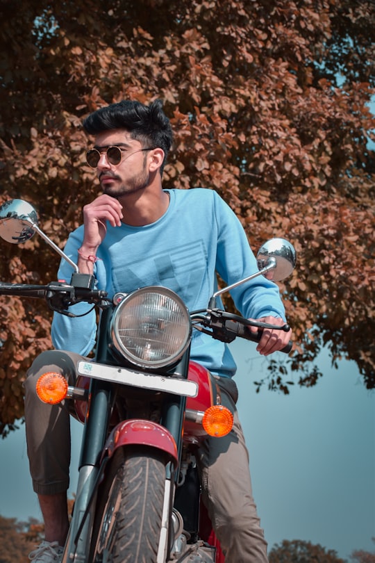 man in blue crew neck shirt riding red motorcycle during daytime in Chandigarh India