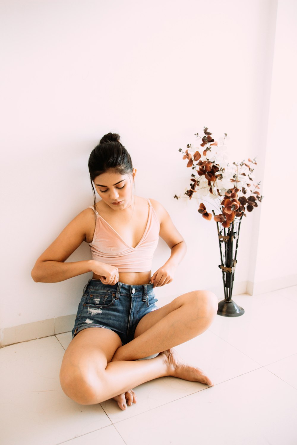 Frau in braunem Tanktop und blauen Jeansshorts sitzt auf Barhocker