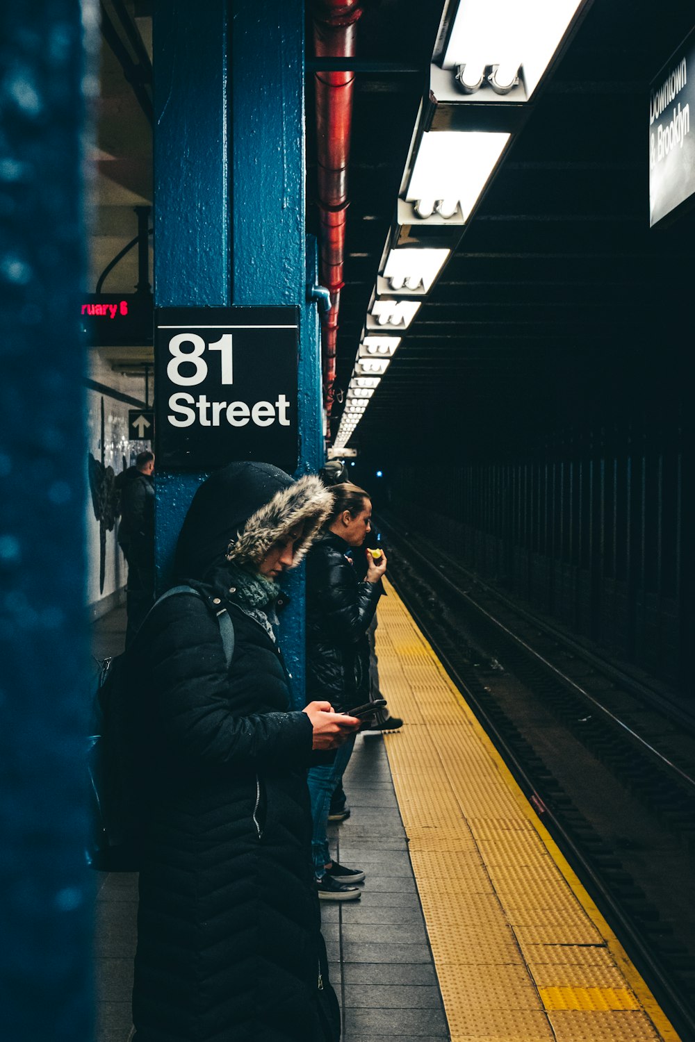 woman in black jacket taking photo of train station