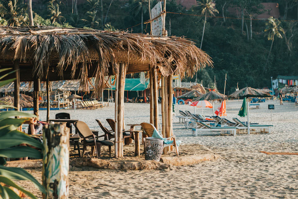 Loungers under a thatched beach shack on a Goan beach