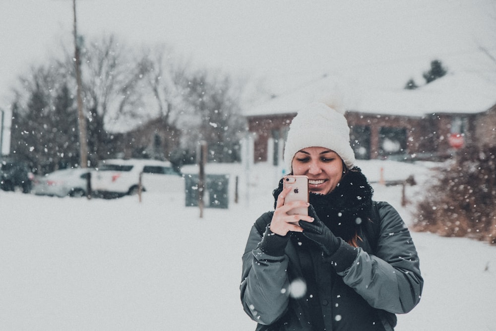 man in black jacket and white knit cap holding black smartphone during daytime