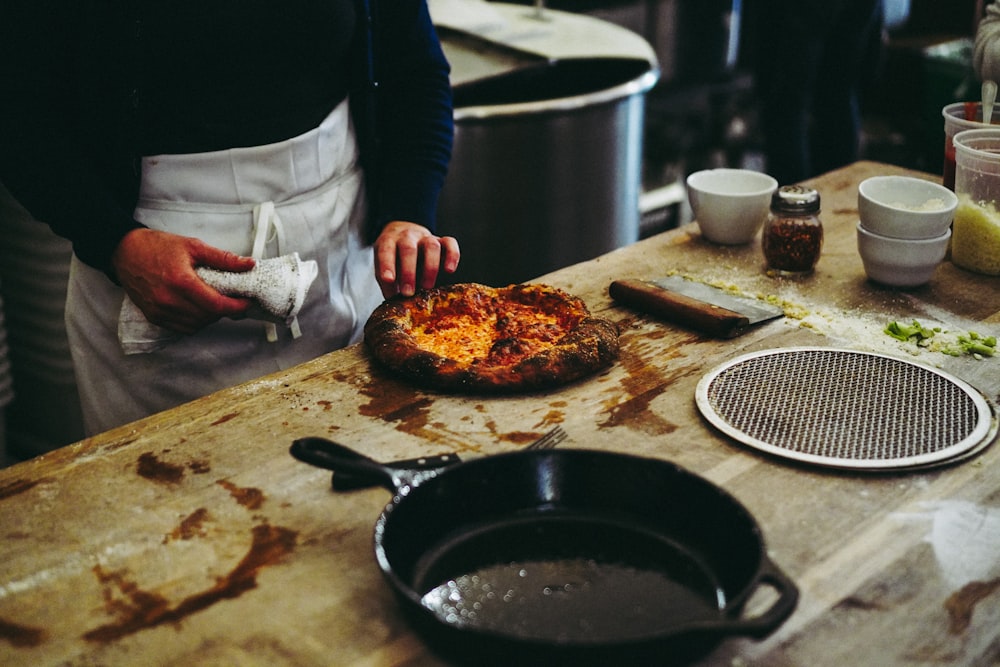 person holding black frying pan with cooked food