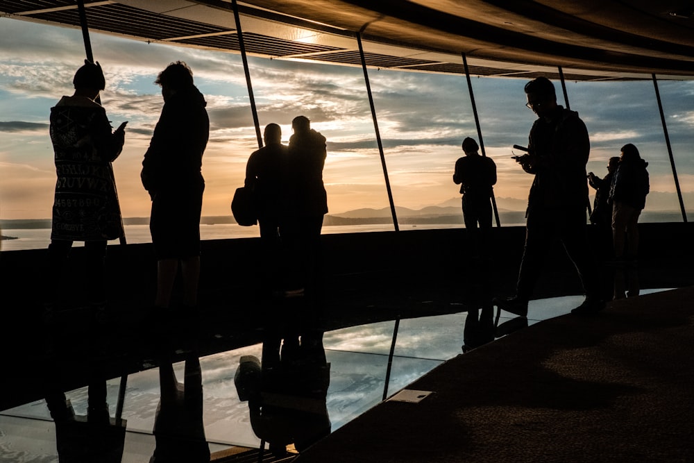 silhouette of people standing on dock during sunset