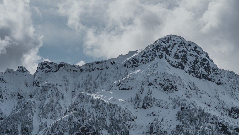 montanha coberta de neve sob céu nublado durante o dia