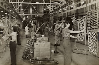 grayscale photo of woman in floral dress standing near bicycle