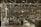 A large industrial factory setting is filled with numerous workers busy at their stations. The space is organized with rows of workbenches and various industrial machinery. Overhead lighting illuminates the expansive area, while large signs hang from the ceiling indicating different sections such as 'Bay D.2 D.3'. The scene conveys a bustling atmosphere typical of mid-20th century manufacturing environments.