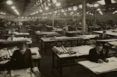 An outside view of a furniture factory with workers collaborating on designs.