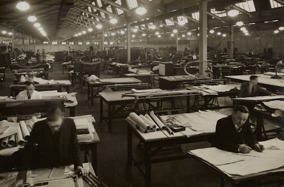 Photograph of skilled workers assembling sturdy school desks in a bright, modern factory setting.
