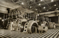 Technicians working on heavy mining machinery inside a spacious, well-lit workshop.