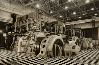 Technicians working on heavy mining machinery inside a spacious, well-lit workshop.