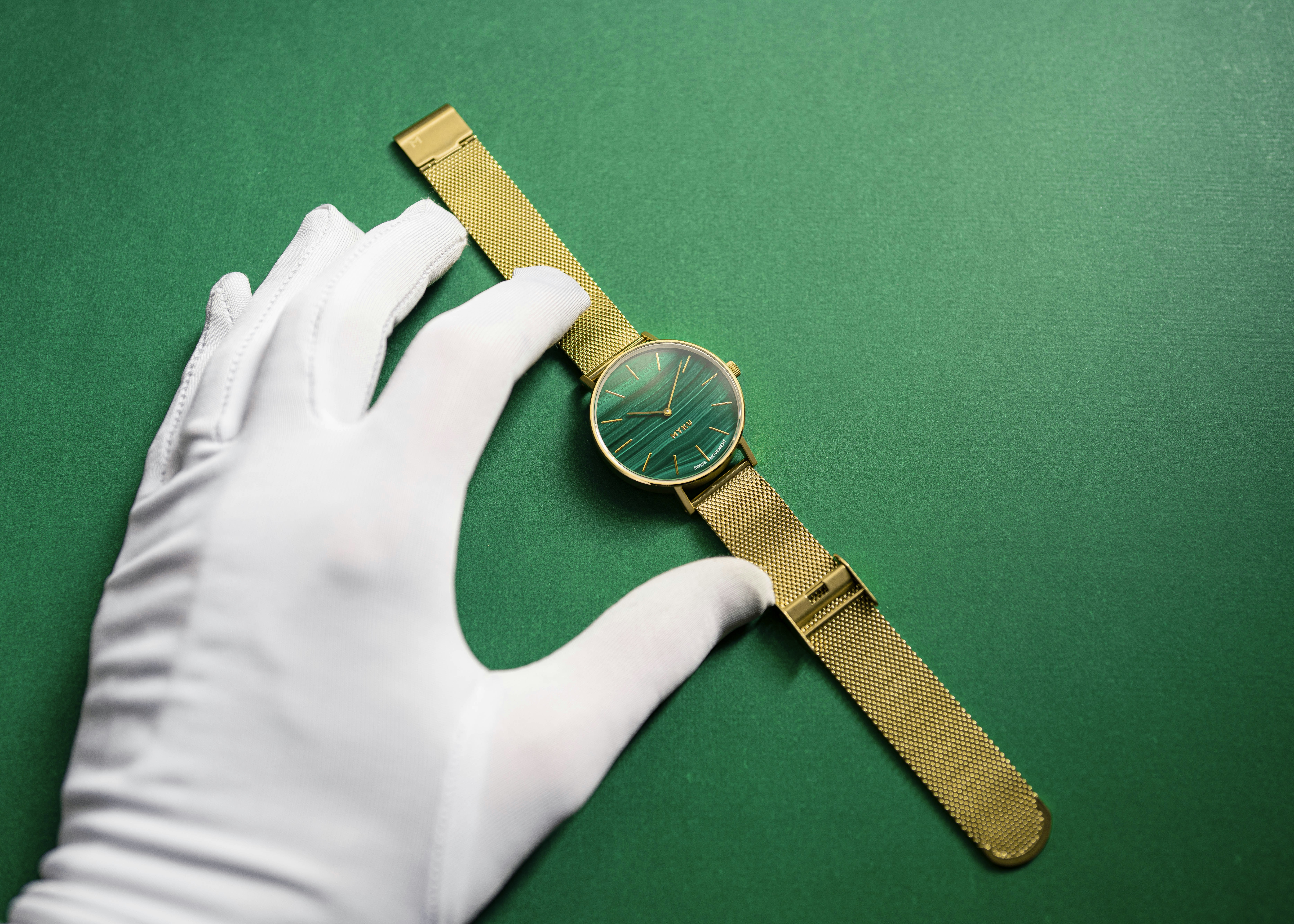 goldene und silberne runde Analoguhr mit braunem Lederarmband