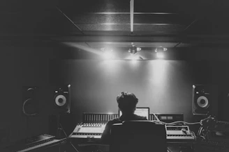 man in black shirt standing in front of black and white piano