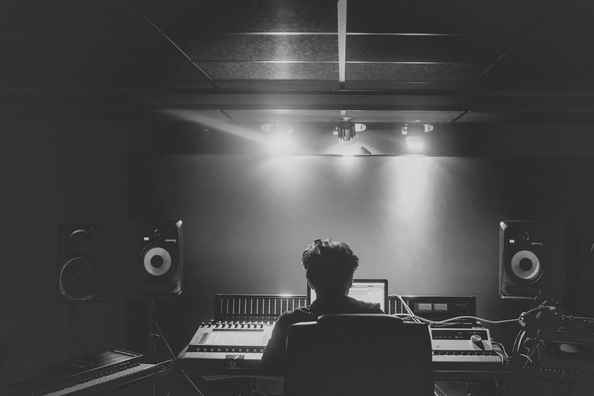 man in black shirt standing in front of black and white piano