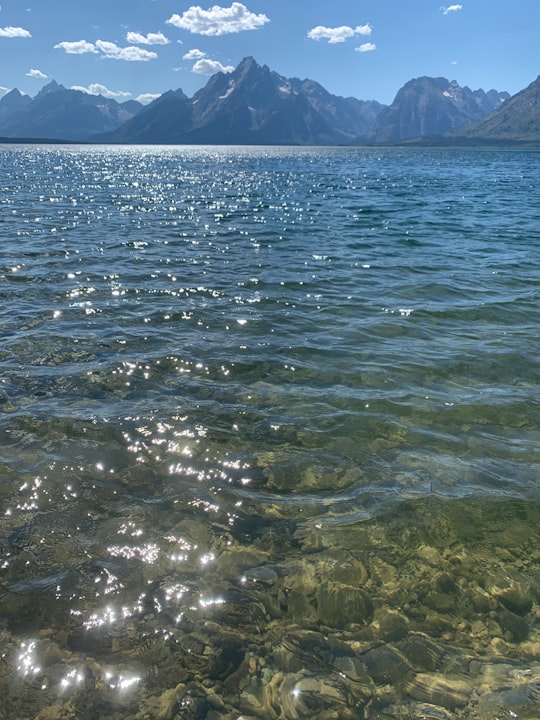 body of water near mountain during daytime in Grand Teton National Park United States