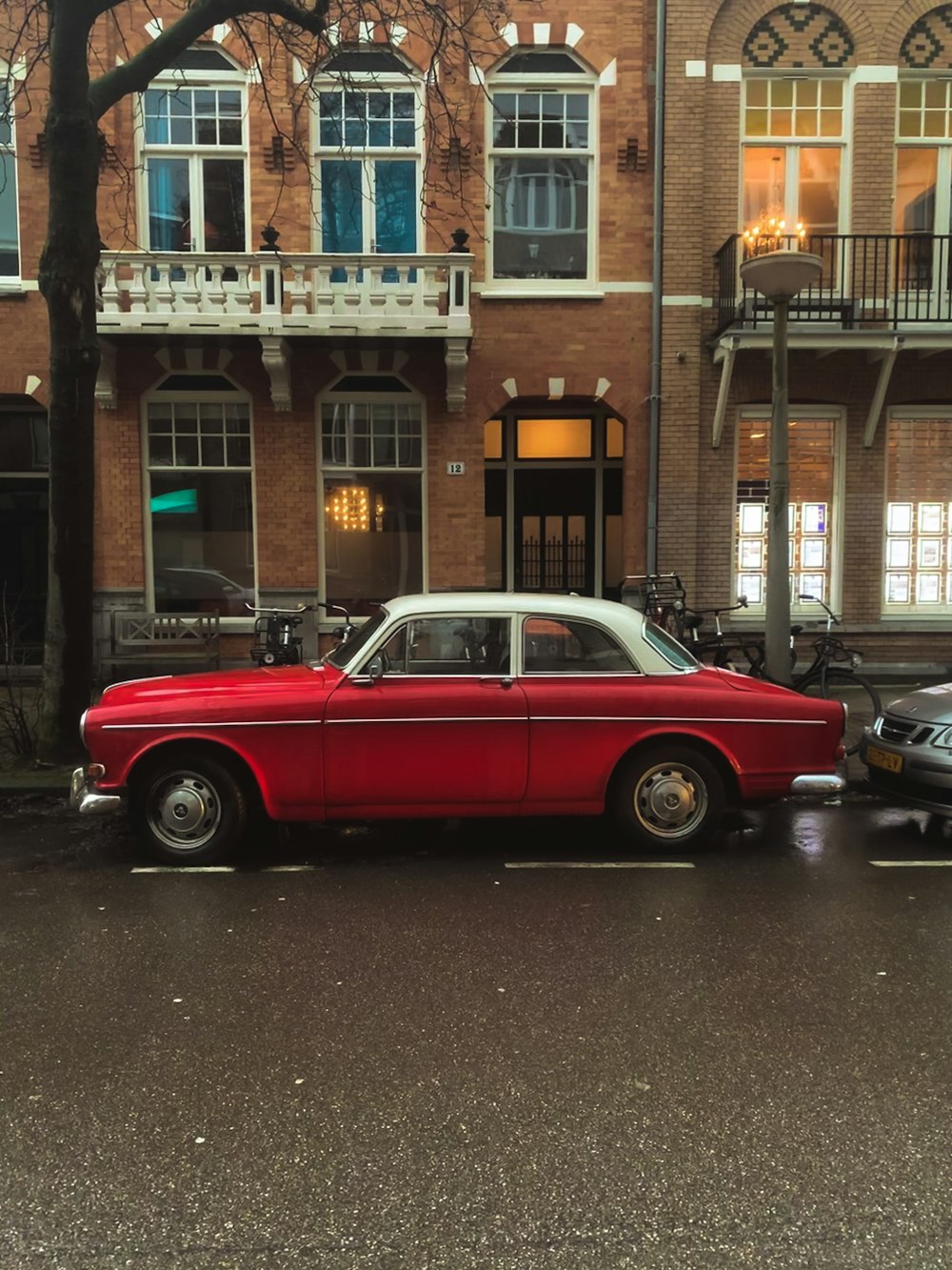 red classic car parked beside brown concrete building during daytime