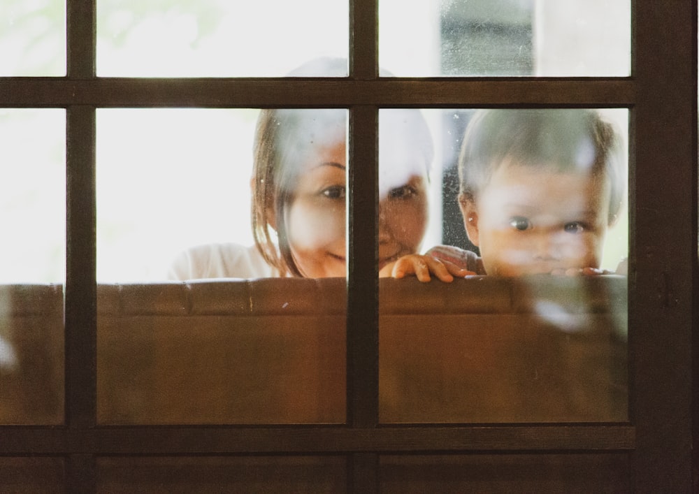 girl in white shirt standing beside glass window