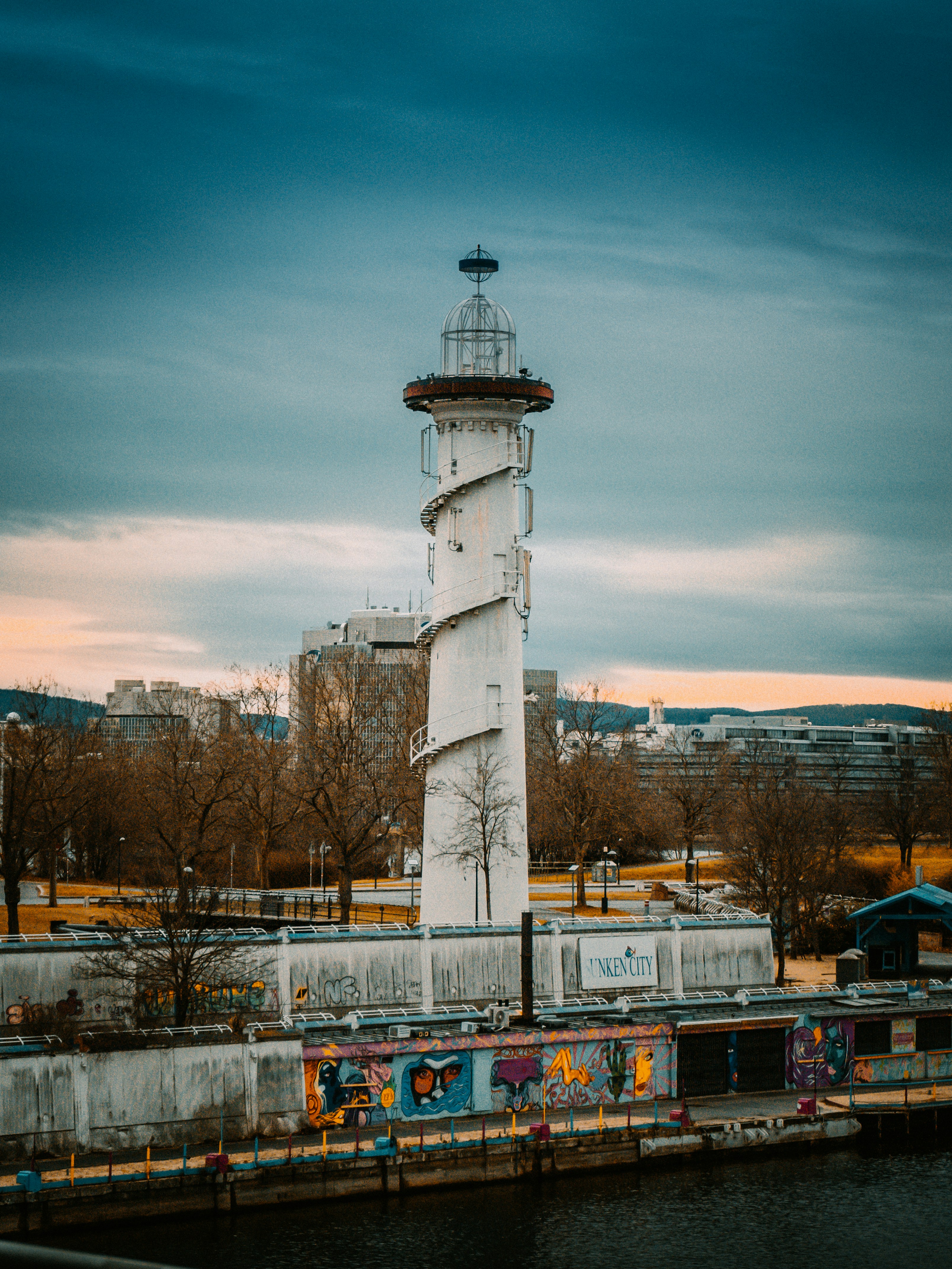 weißer und schwarzer Leuchtturm in der Nähe von kahlen Bäumen unter blauem Himmel tagsüber