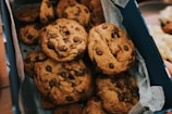 A happy customer holding a box of warm cookies with melted chocolate.