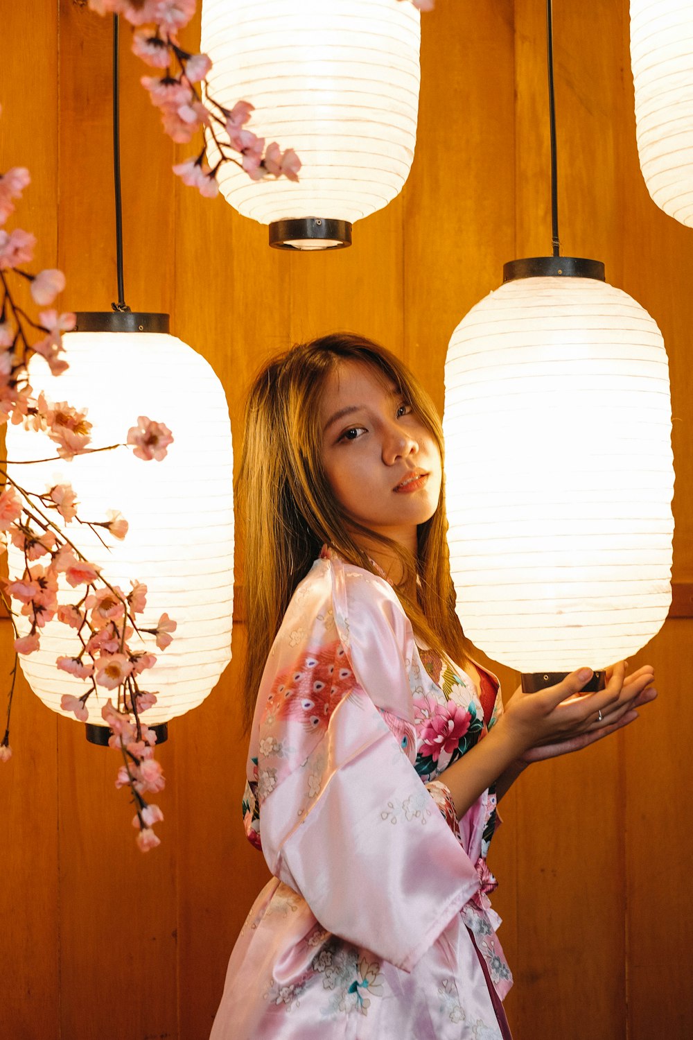 woman in white and pink floral robe holding white and brown flower