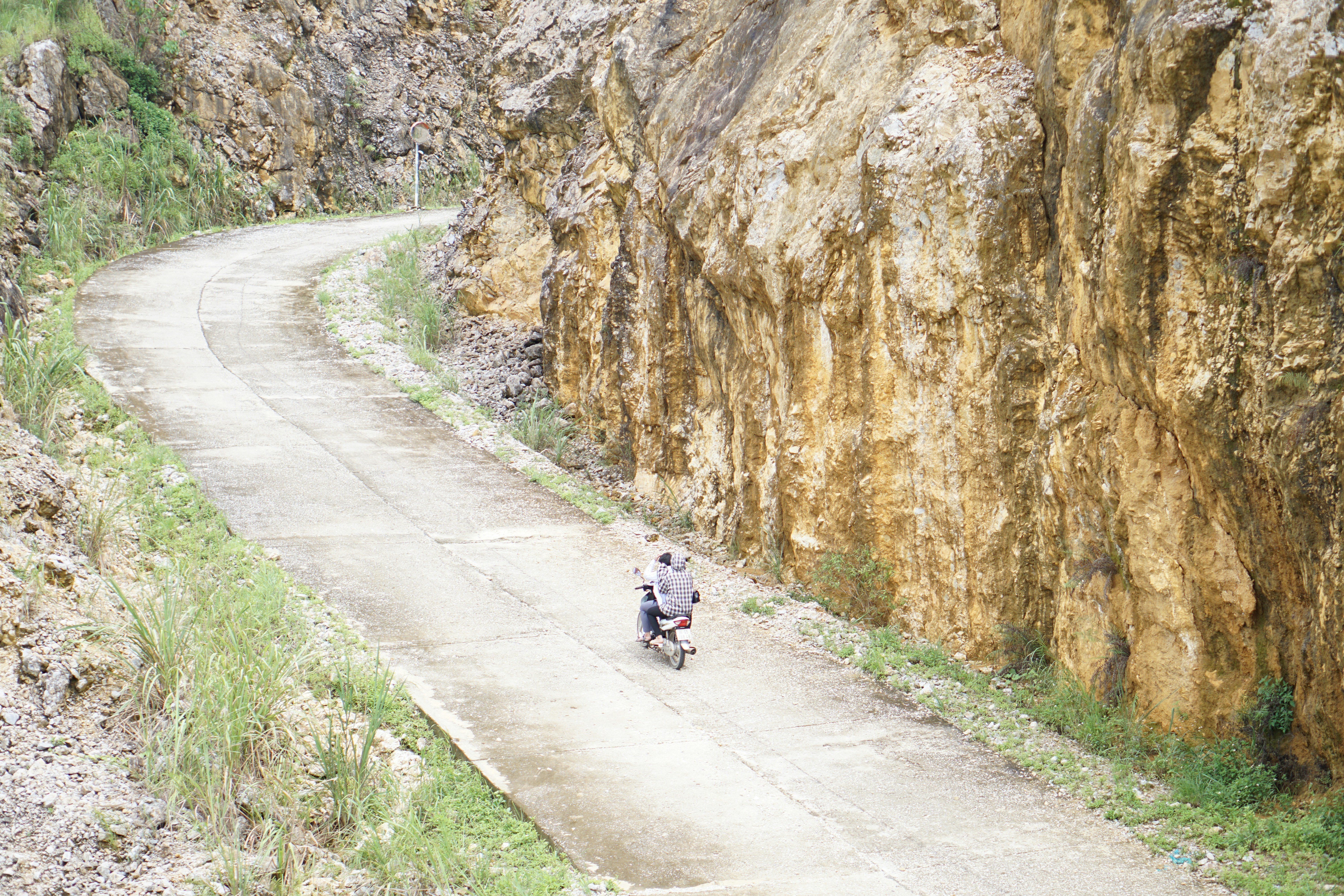 man in black jacket and black pants riding on black motorcycle near brown rocky mountain during