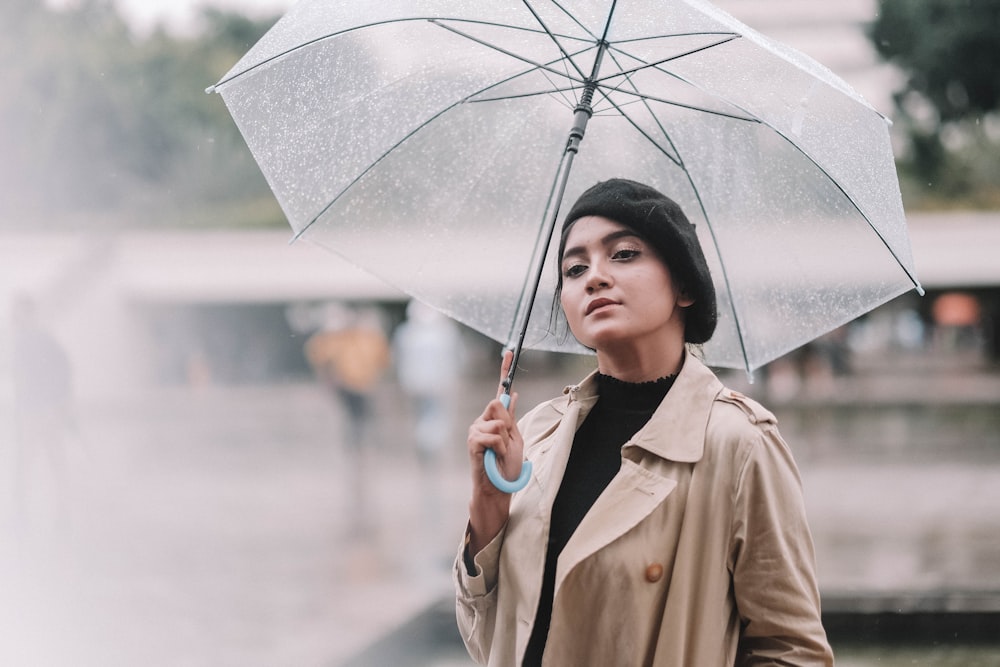Frau im braunen Mantel mit Regenschirm