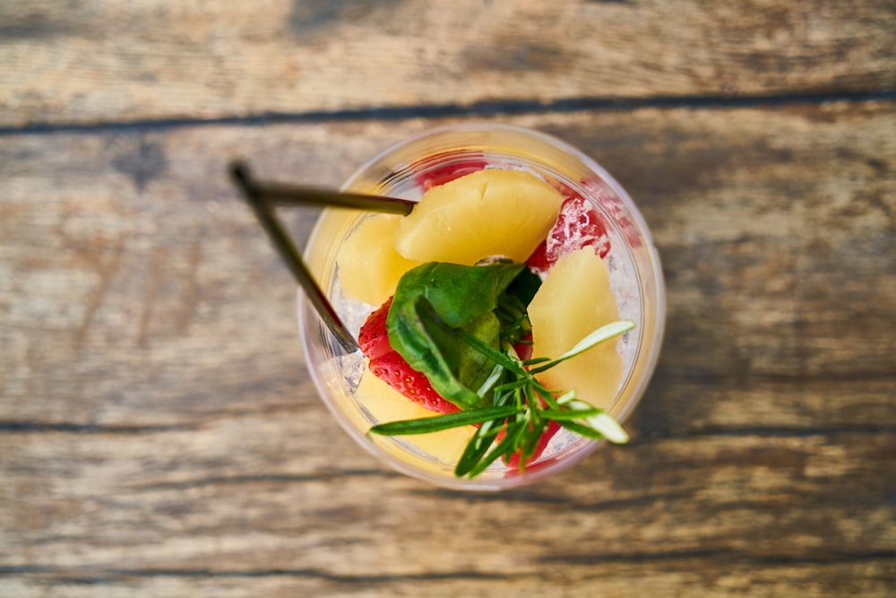 a glass of fruit and ice on a wooden table