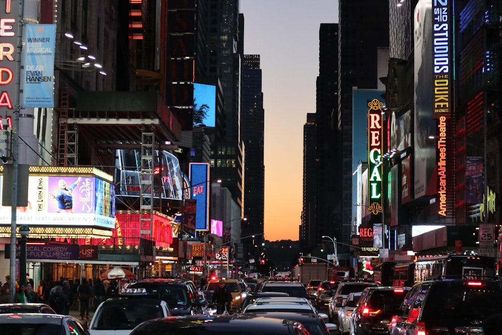 cars on road between high rise buildings during night time