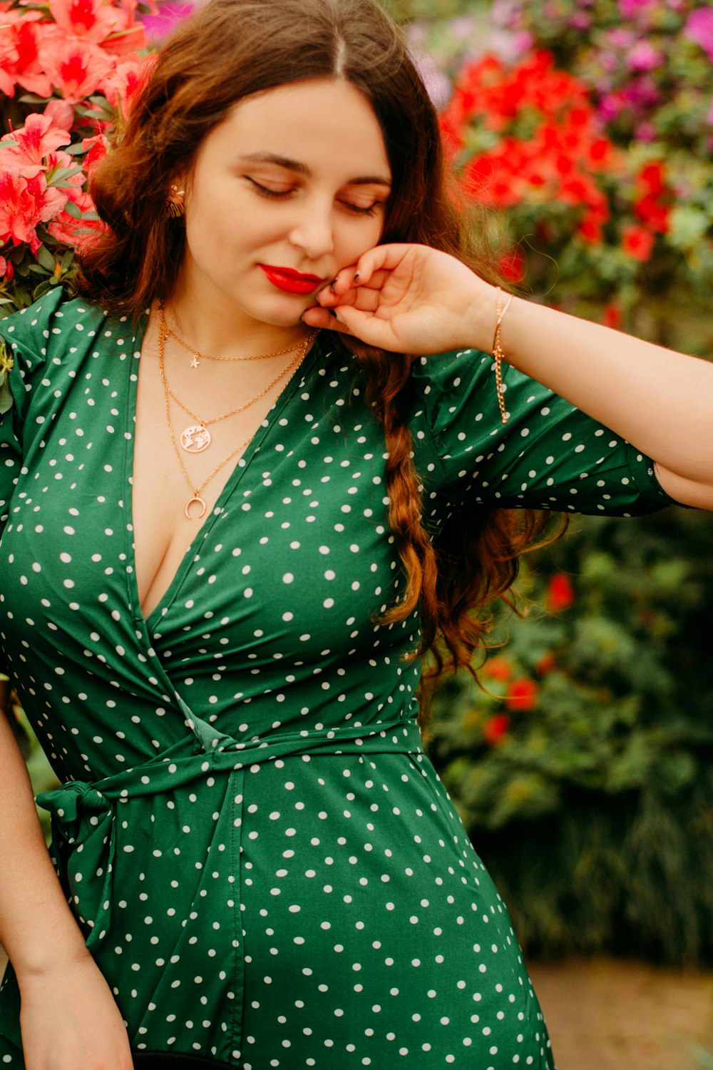 woman in green spaghetti strap dress holding red flower