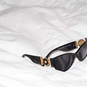 a pair of sunglasses laying on top of a bed