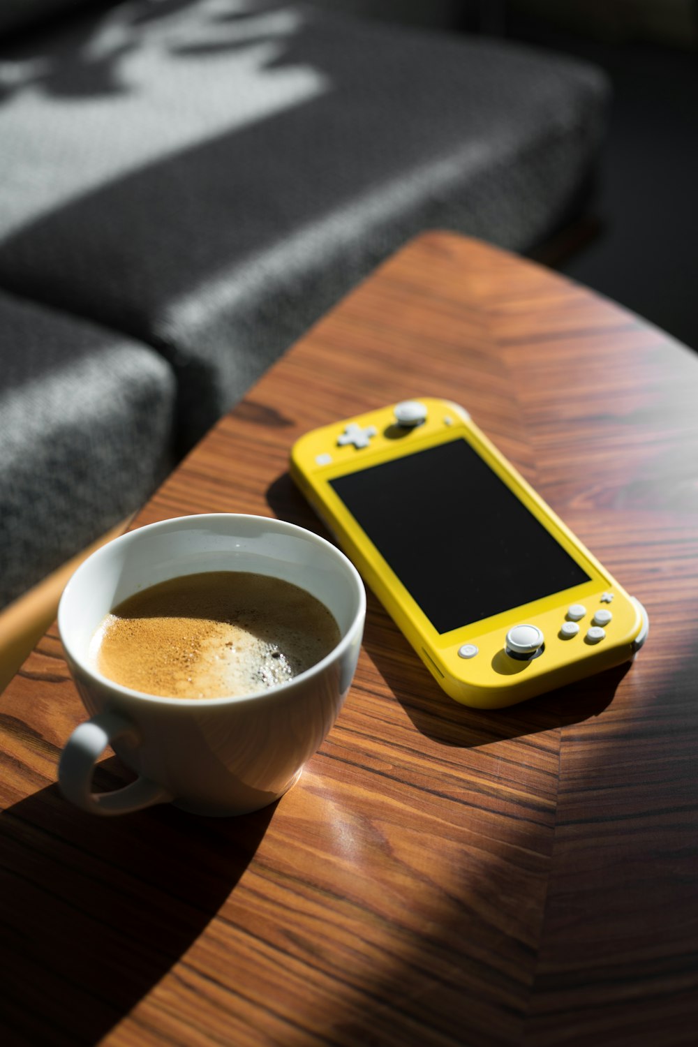yellow iphone 5 c beside white ceramic mug on brown wooden table