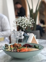 A rustic wooden table set with a plate of quinoa salad featuring roasted vegetables and herbs.