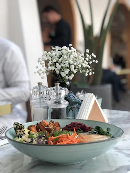 A vibrant bowl of protein-packed quinoa salad with colorful veggies and grilled chicken, styled on a rustic wooden table.