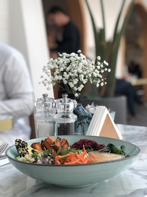 A colorful, fresh quinoa salad served in a bowl with vibrant vegetables on the side